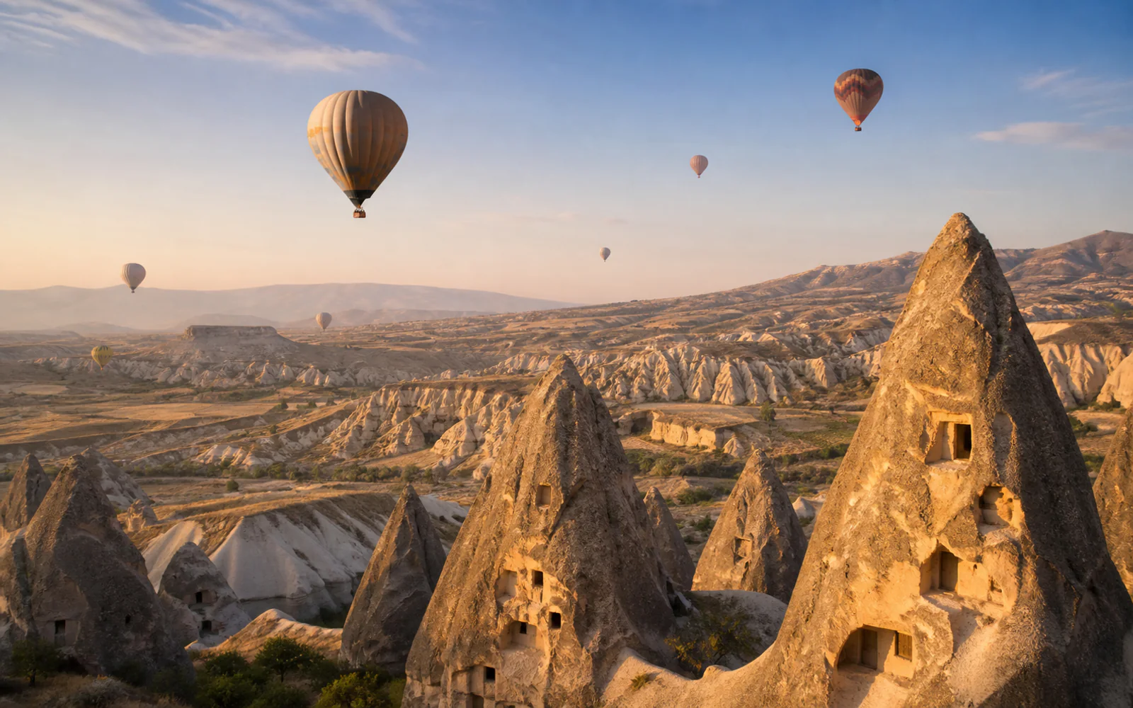 Hot-air balloons above Cappadocia’s fairy chimneys and cave dwellings at sunrise